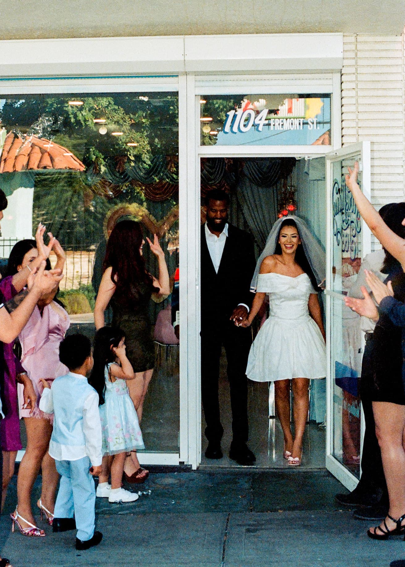 Newlyweds walk out of 1104 Fremont Street as guests clap