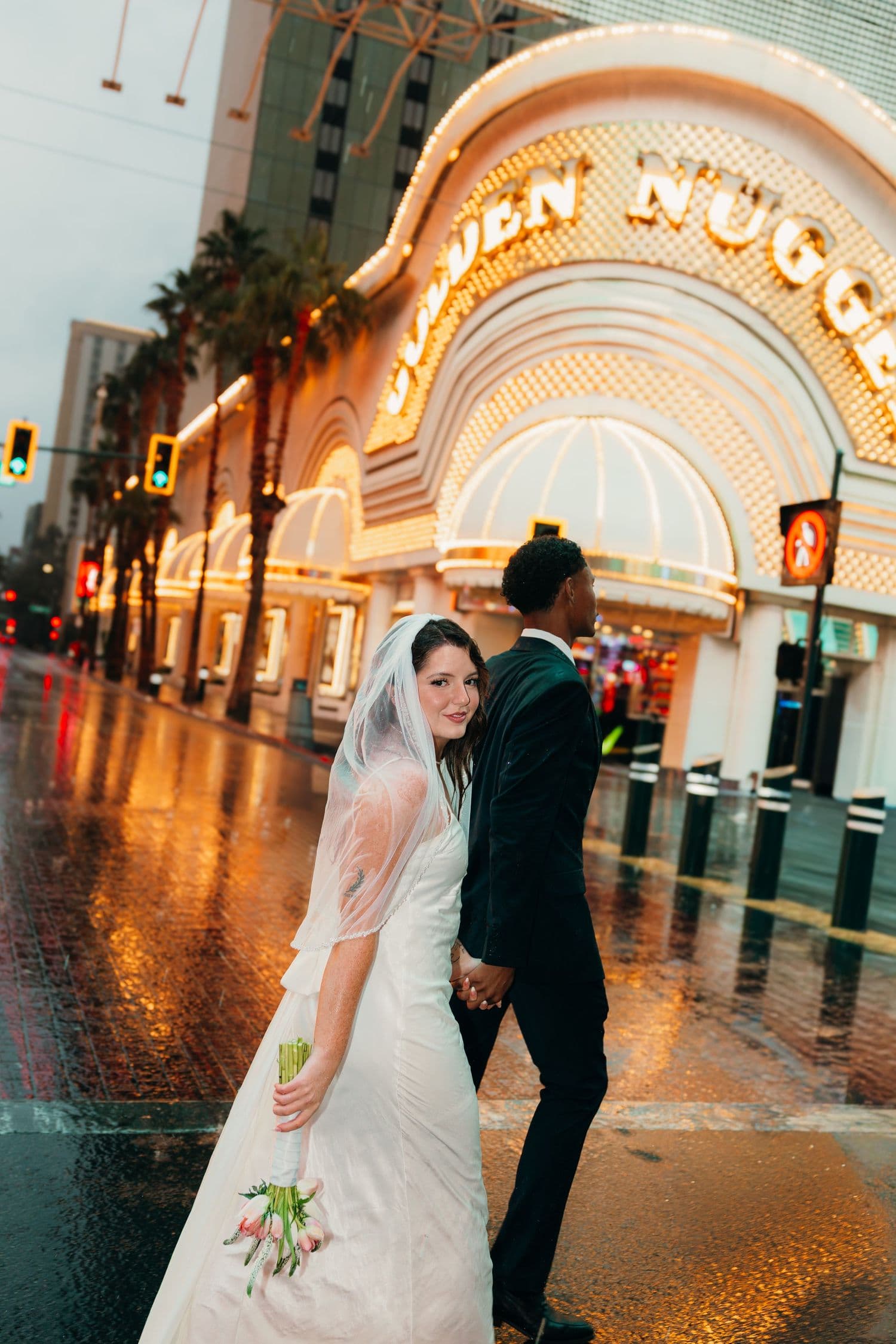 A couple holding hands outside the Golden Nugget in Las Vegas on a rainy evening